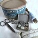 Vintage sewing kit with scissors, lace, lace bobbin, buttons, tin box, pincushion, thimble