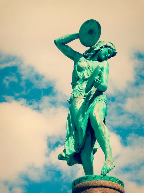 Cymbal Player: fine art photograph print of a green statue of a woman playing music against the blue sky with clouds (Indianapolis)