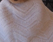 White, hand knitted baby blanket in a zig zag design for a boy or a girl