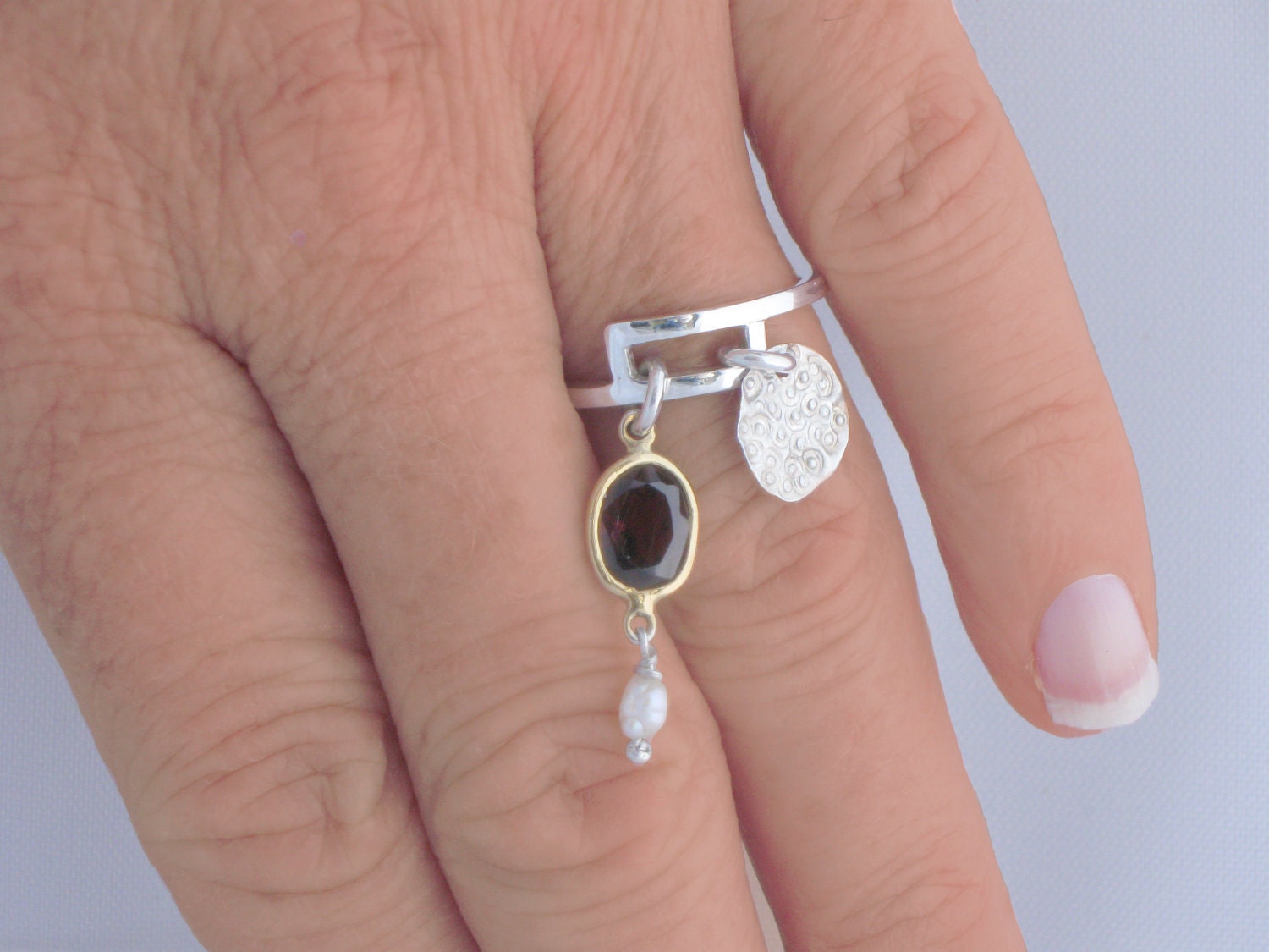 Sterling silver charm ring with pattern motif and faceted garnet and white seed pearl
