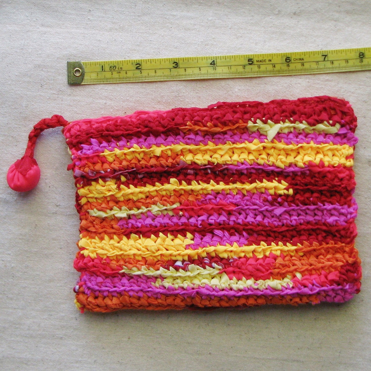 Zippered pouch crocheted in sunset stripes from colorful eco-friendly upcycled yarn, 7.5" by 5.5", red orange yellow pink coral