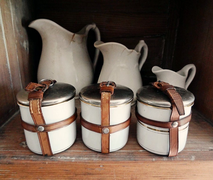 vintage enamelware canisters, 3 small tins with leather straps, white with gold striping from Germany