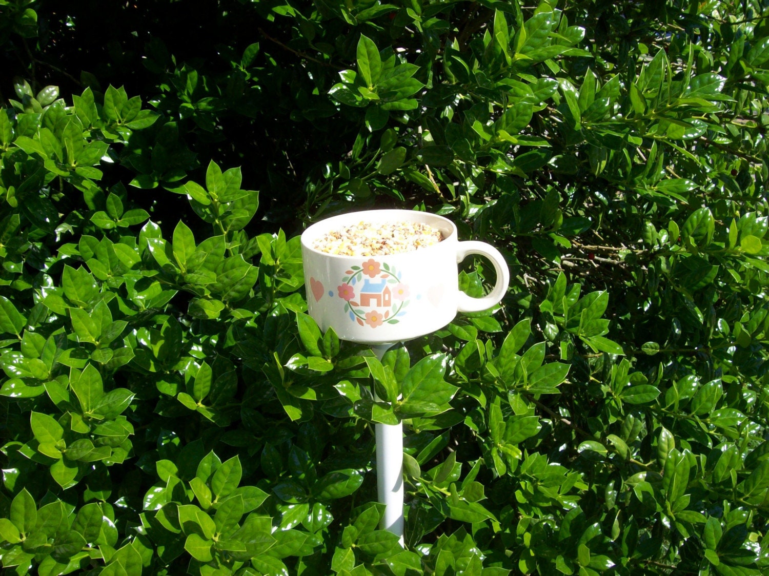 Teacup birdfeeder poke creates a charming addition to your flower garden