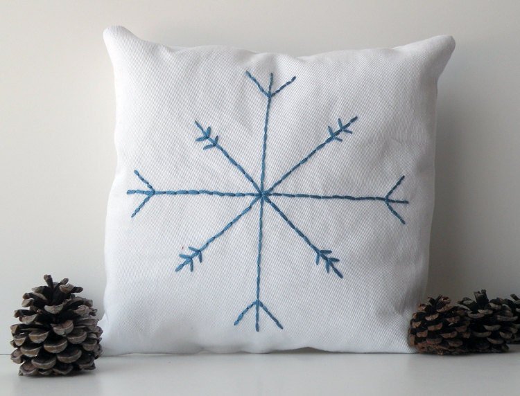 Small white cotton decorative pillow with blue embroidered snowflake