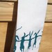 Cotton huck tea towel with teal dancing rabbits screen print pom pom trim