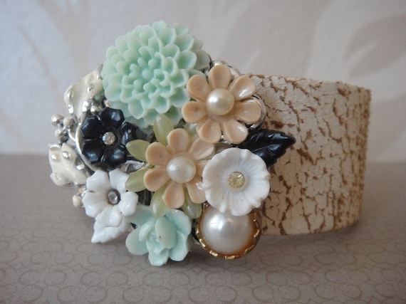 Made with some vintage and non-vintage stuff, like some vintage salmon coloured lucite flowers, vintage pearls, mint green flower cabochons, a real vintage black and white flower earring, a vintage faux pearl button and a tiny dainty ivory white vintage flower.