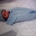 A soft hand knitted baby cocoon and hat set.