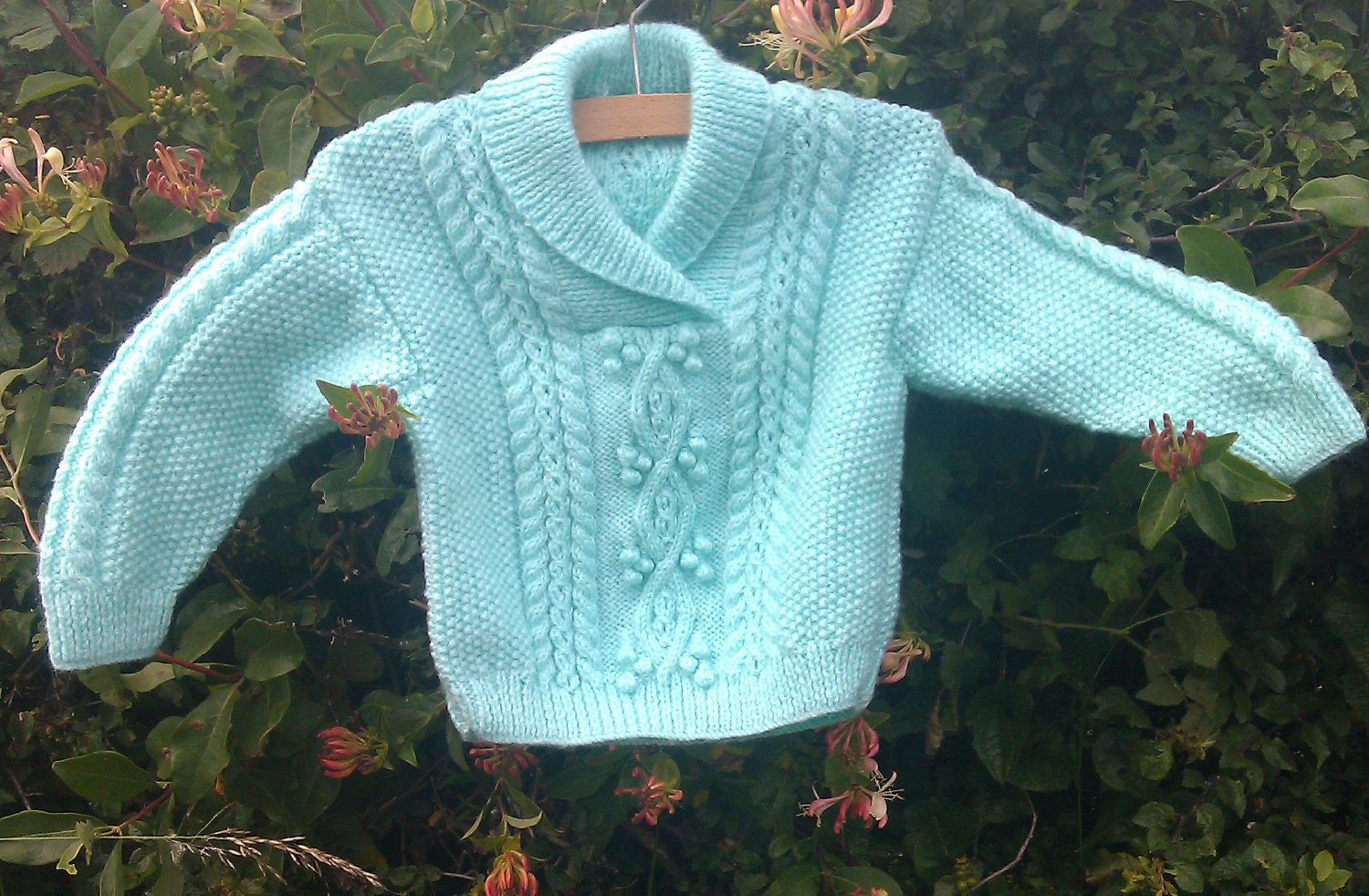 Child's handknit pale green aran sweater with shawl collar.