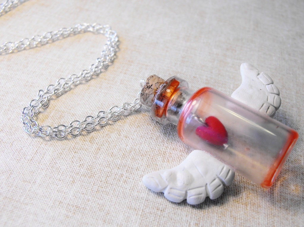 Winged Heart necklace- polymer clay wings are glued to the outside of a red tinted bottle with a heart inside