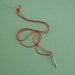 Silver arrow pendant on red silk cord