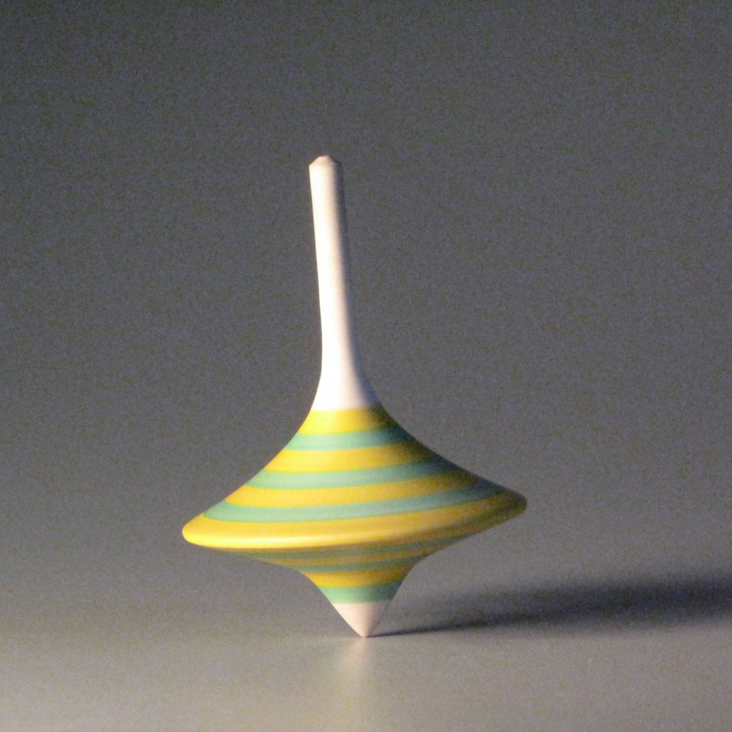 Funnel shaped spinning top with yellow & aqua stripes