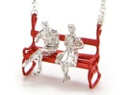 Silver necklace with a with a couple in love sitting on red bench