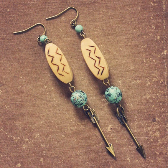 arie.  a pair of wood and teal arrow earrings.