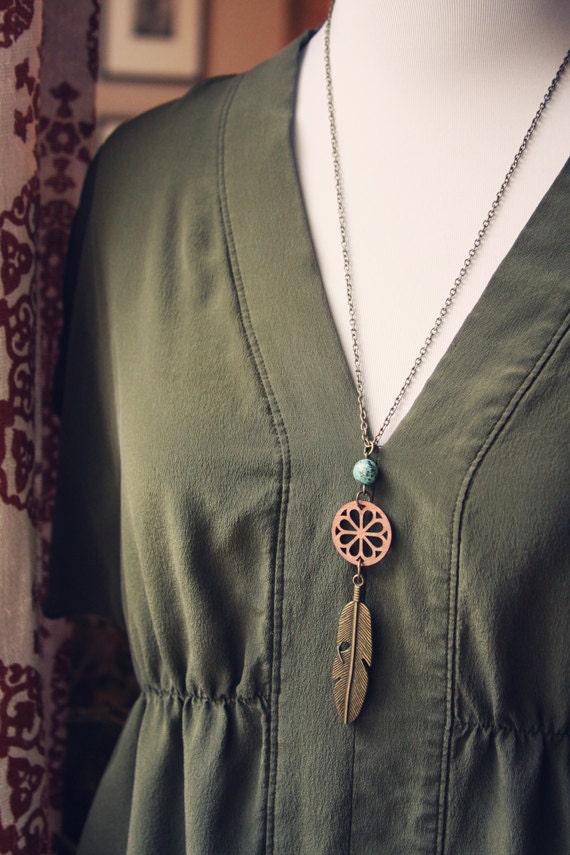 thea. a wood and brass feather necklace.