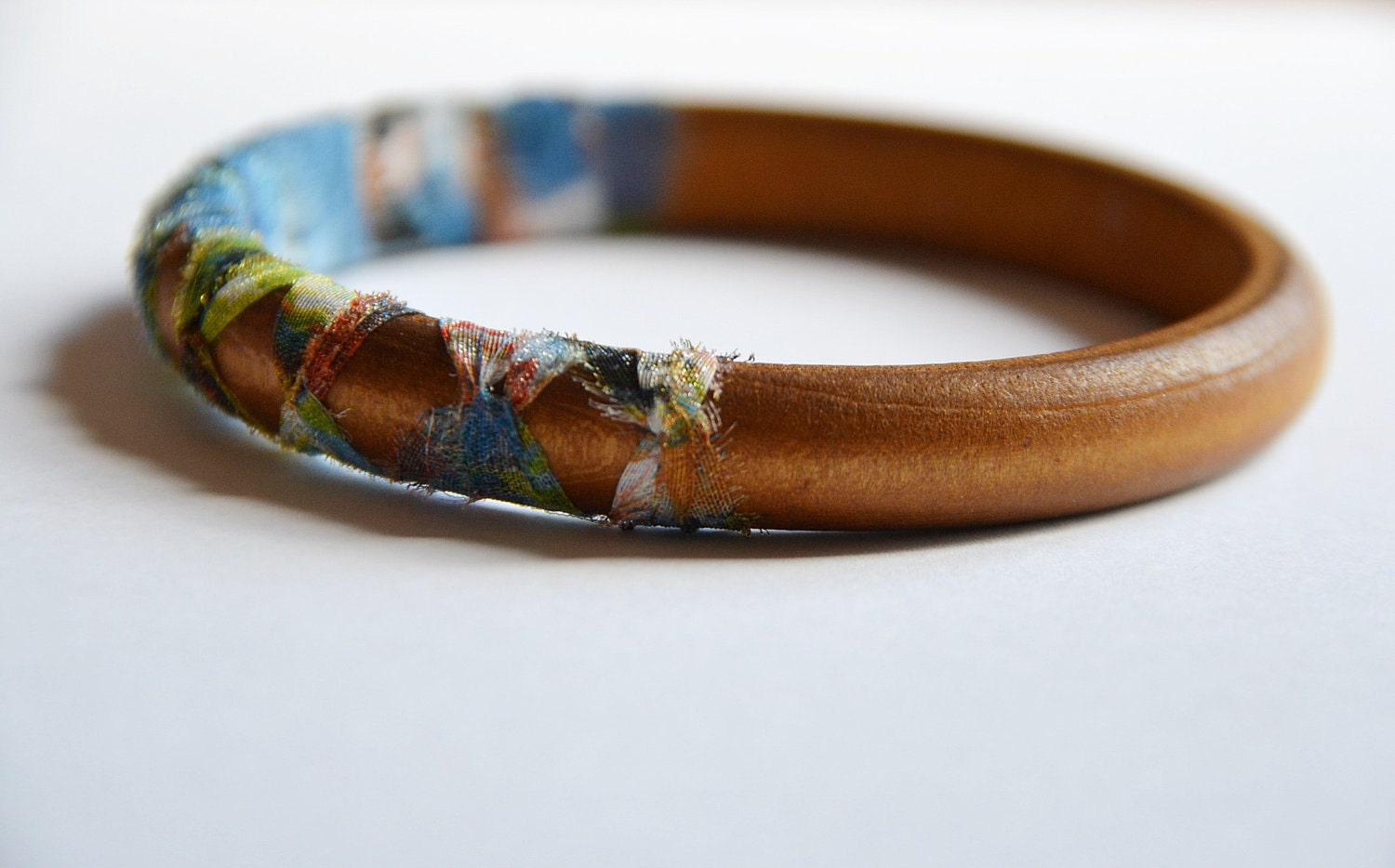Wood and fabric bangle. Summer tribal fabric hand knotted around wooden bangle. Blue/green color. Light weight Small size.