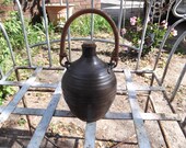 brown/green pottery jug with cane woven handle