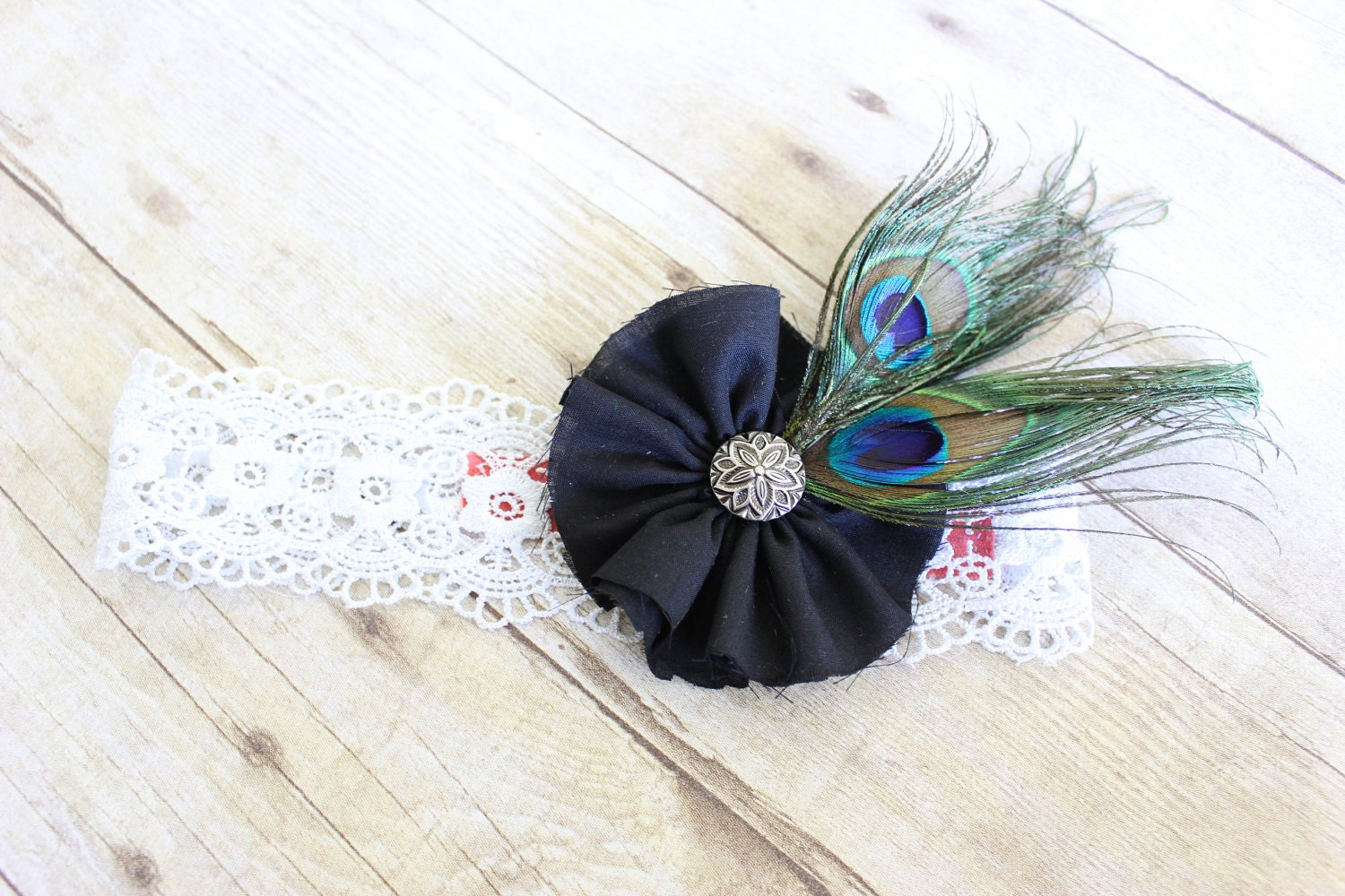Black fabric flower on a lace headband with peacock feathers