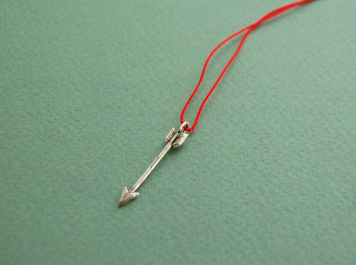 Silver arrow pendant on red silk cord