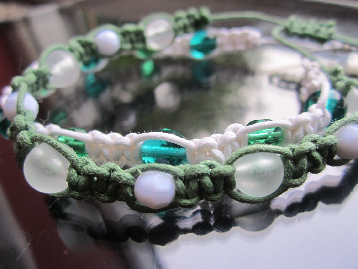 Two beaded macrame bracelets one green with white beads and one white with green beads