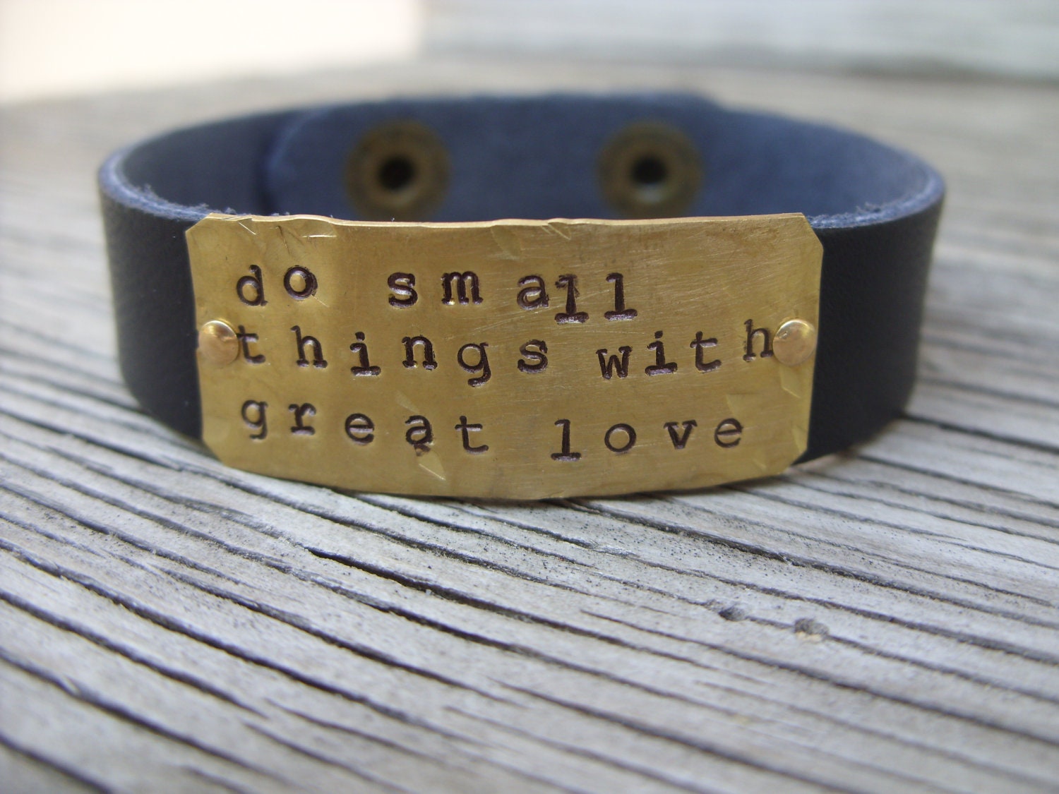 A riveted, brown leather cuff bracelet with hand stamped brass do small things with great love- distressed and embellished wording