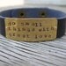 A riveted, brown leather cuff bracelet with hand stamped brass do small things with great love- distressed and embellished wording