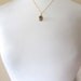 Gold skull charm necklace on delicate 14k gold plate chain, satin finish