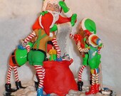 SANTA'S WORKSHOP FIGURINE with his elves helping fill his bag with toys on his list.  Polymer clay. 8" tall