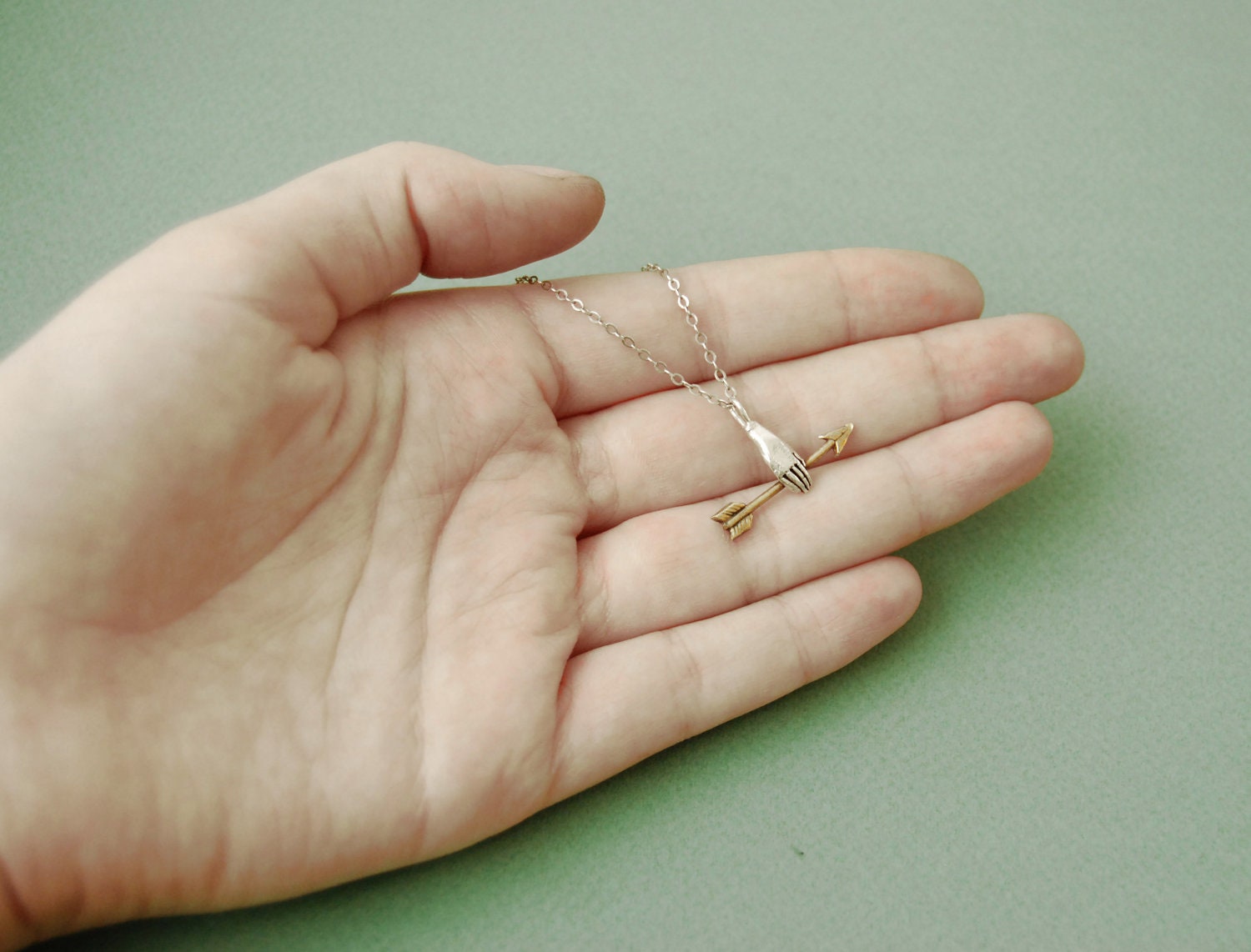 Hand with golden arrow necklace