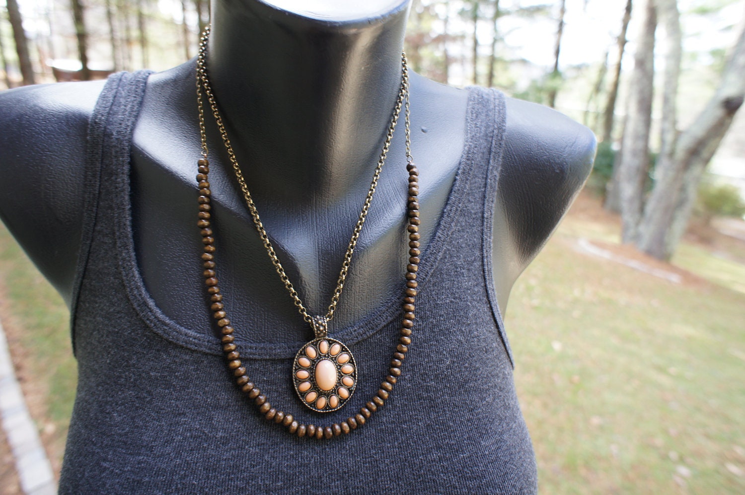 Medium length, double layer necklace with brown wooden beads, antiqued gold chain, and pink stone medallion style charm