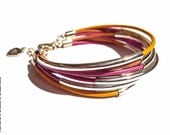 Yellow, fucsia, natural bracelet with leather ropes and silver tubes.