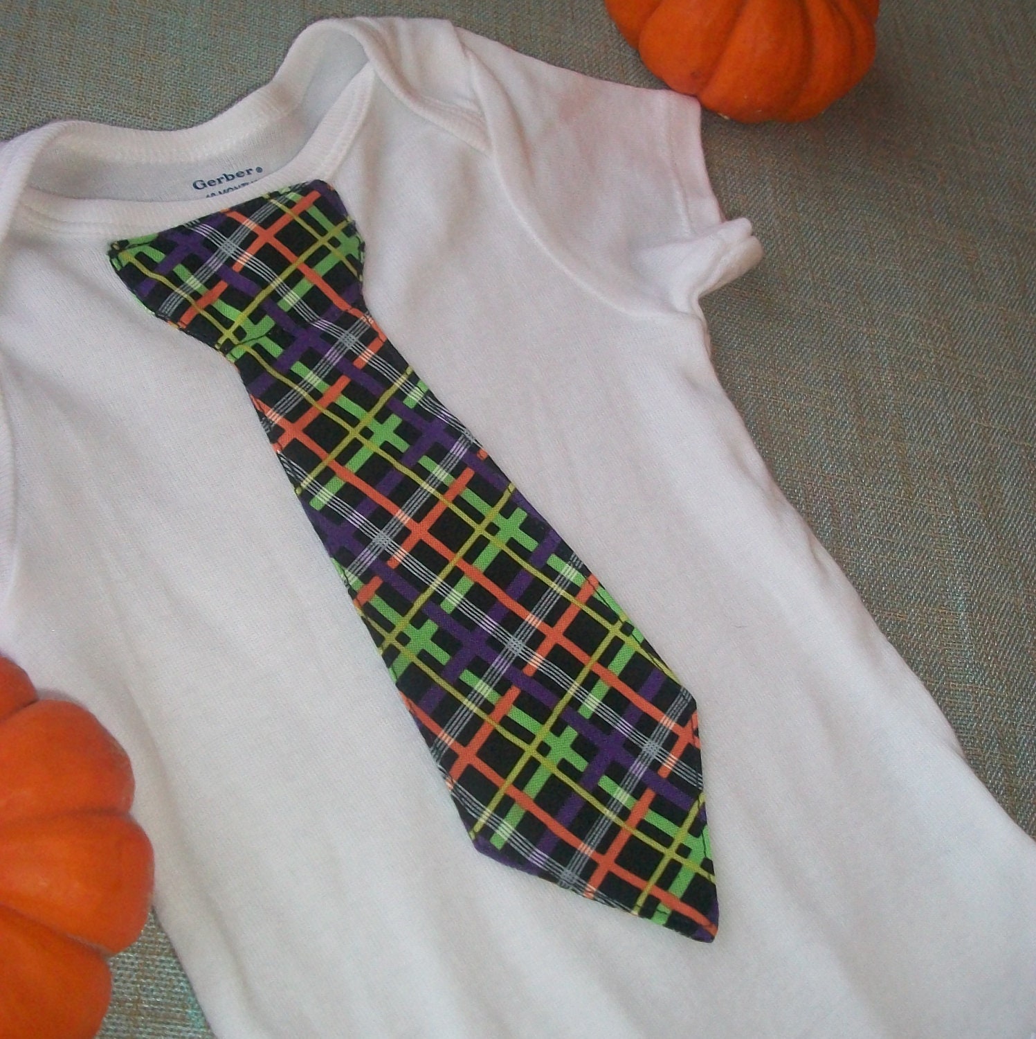 Order now in time for Christmas. Baby onesie with bright colored stripe plaid tie.