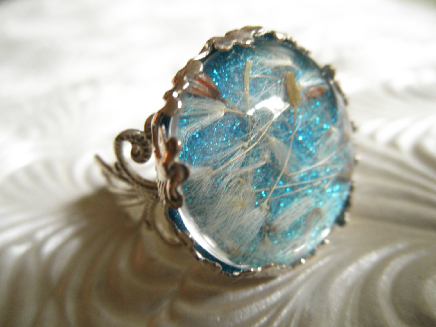 Ride The Wind-Victorian Filigree Glass Ring with Dandelion Seeds Atop Sparkling Waters Shimmering Turquoise Background, Symbolizes Happiness