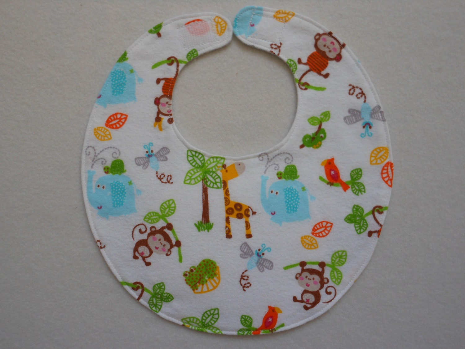 Baby bib, four soft layers, reversible, white with elephants, giraffes, and monkeys