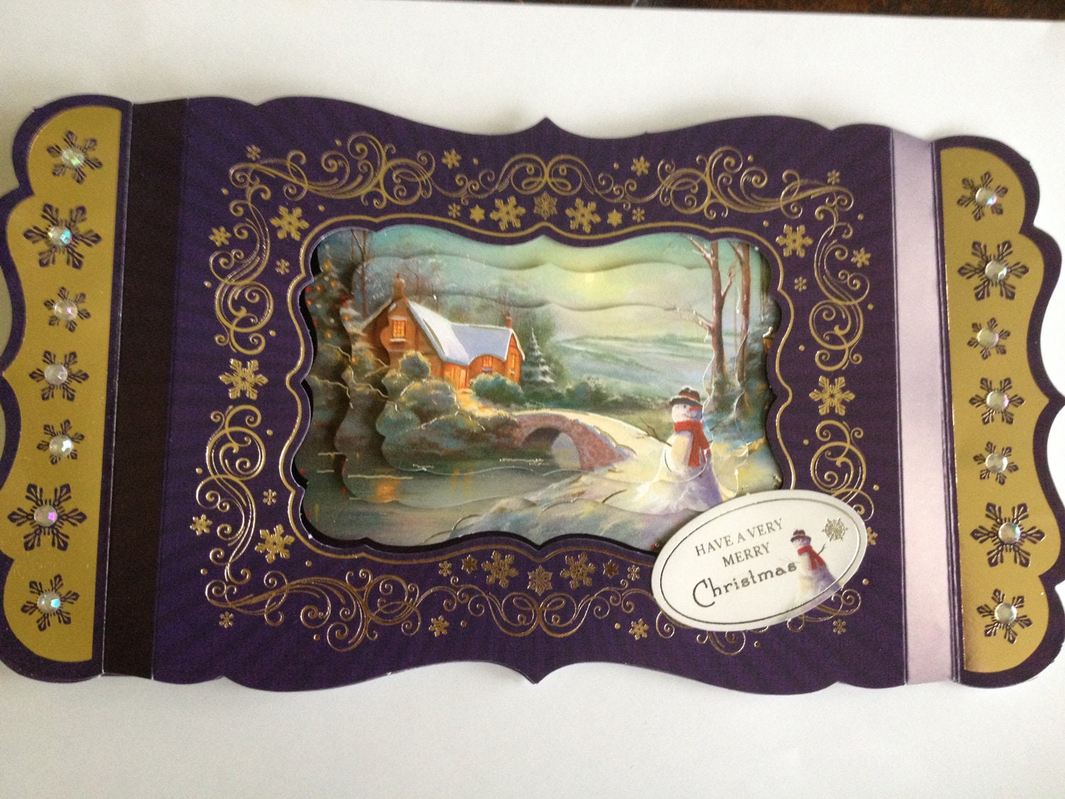 purple and gold christmas card, snowflakes and swirls, cottage, snowman scene, beads