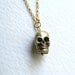 Gold skull charm necklace on delicate 14k gold plate chain, satin finish