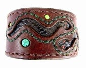 Brown leather wristband with serpent cutouts and bead inlay.
