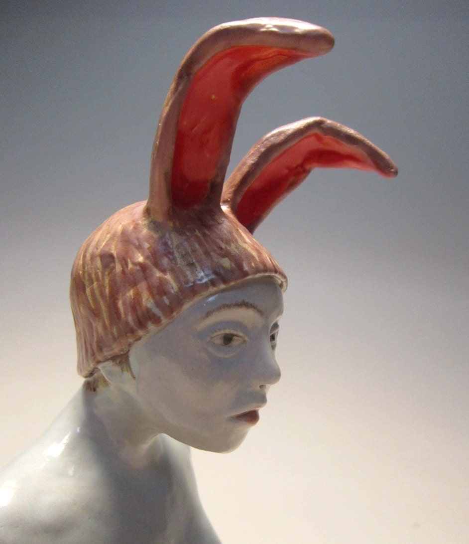 Woman in dream - ceramic figurative sculpture of white glazed female figure with rabbit ear cap by Carrianne Hendrickson.