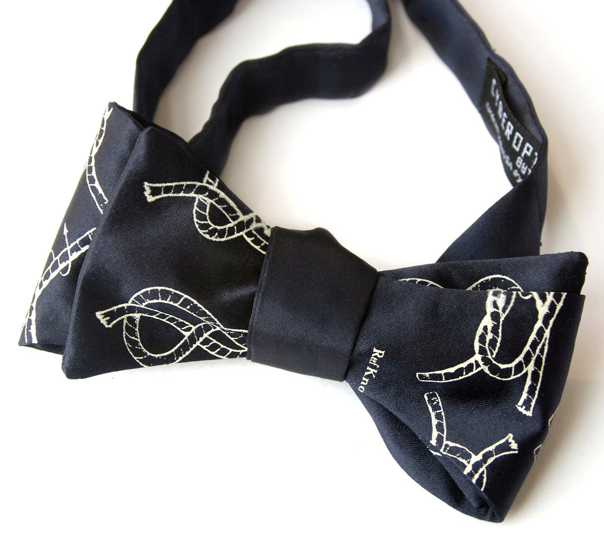 Navy blue bow tie, knot-tying diagram. "KNOTical." Men's bowtie, freestyle. Silkscreened ivory-cream print.