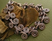 Antiqued copper bracelet featuring Egyptian coils or interlocking spiral links