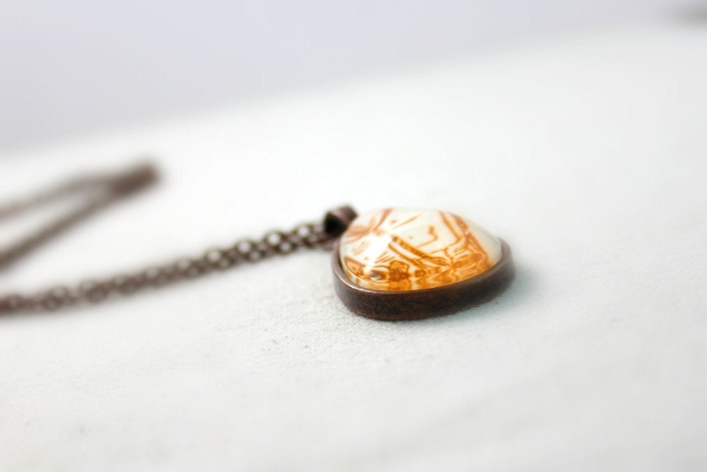 Necklace with victorian gilded age swirl flourish motif in ginger orange rust brown red from vintage sheet music under glass