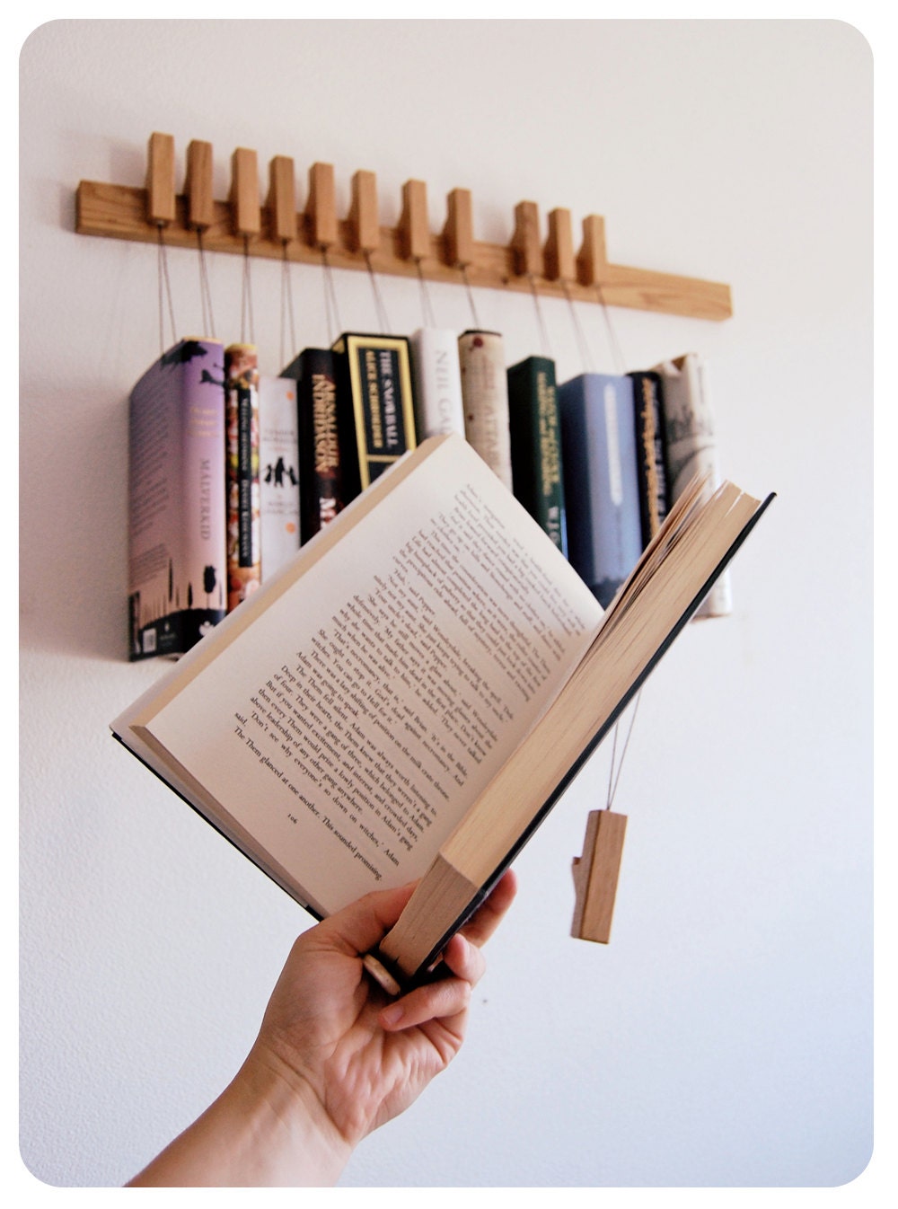 Custom made wooden book rack / bookshelf in Oak. The pins are also bookmarks.