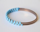 Blue suede bangle. Sky blue suede, herringbone pattern woven together around two bronze colored bangles. Small size.