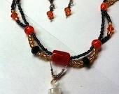 orange,black,and gold beaded scalloped necklace with mini filled glass bottle