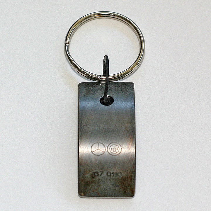 Car Engine Part KEYCHAIN - salvaged MERCEDES Benz part with original stampings of logo and part numbers.  Black velvet backing.