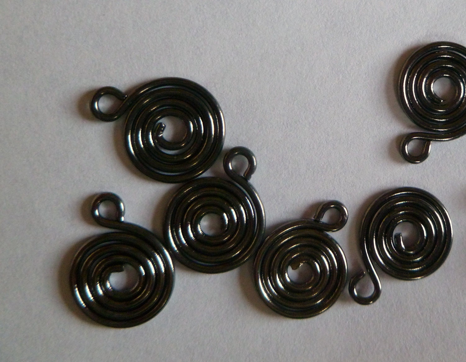 Drop, gunmetal finish, 10mm double-sided flat round with spiral design. Sold per pkg of 50.