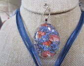 Stunning homegrown pressed apricot Verbena and Periwinkle Forget Me Nots behing handcut crystal clear oval pendant.