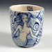 Blue and white porcelain cup with faces and mermaid