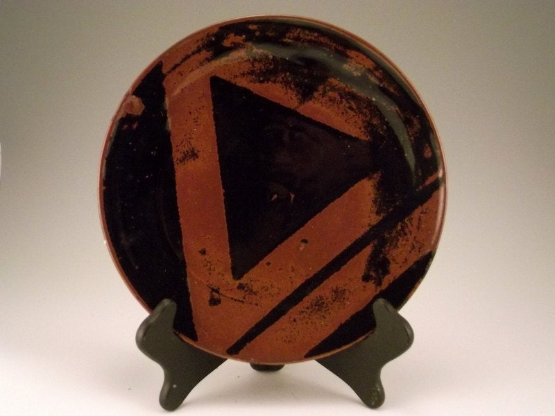 Handmade ceramic plate. Black triangle design across a brown background.