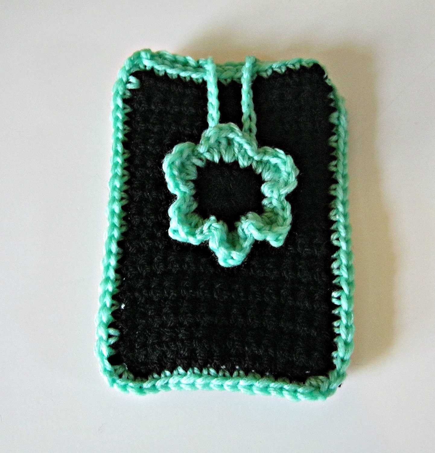 Crocheted phone cover in black with a mint green flower and trim