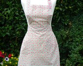 Ladies full length vintage inspired pinny apron in a floral pink and ivy green pattern with two small pockets.